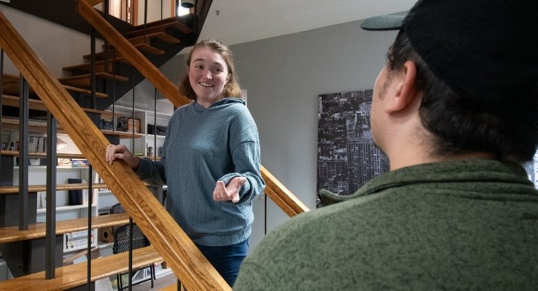 A woman and a man stand together on house stairs, illustrating the emotional toll of drug addiction on family members.
