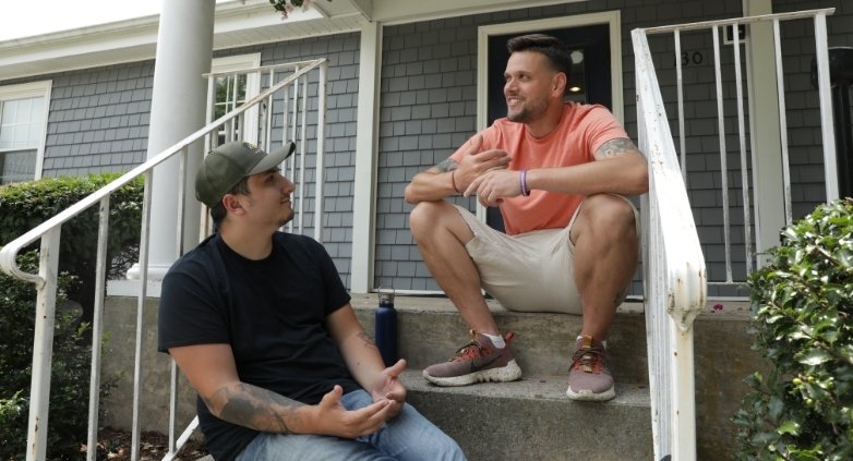Two men on the steps of a house, talking about how to help someone stay sober while maintaining healthy boundaries.