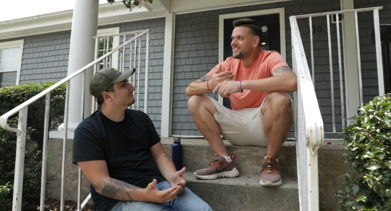 Two men on the steps of a house, sharing insights on the 3 C's of family recovery in addiction support.