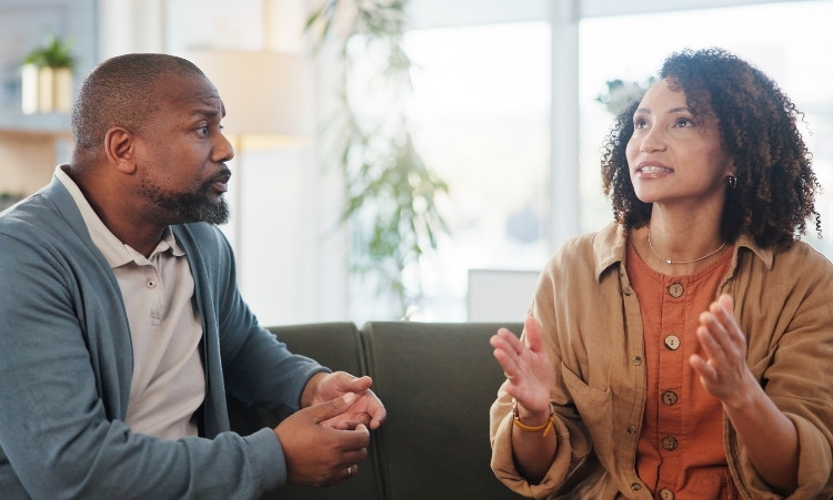 A man and woman engage in conversation in a living room, highlighting a supportive environment for recovery therapy in CT.