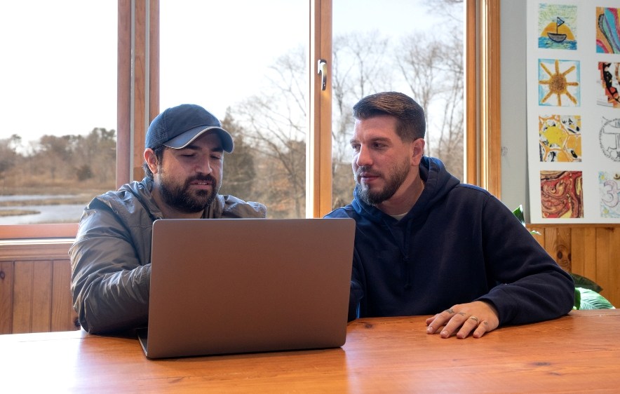 Two men at table with laptop, discussing alcohol abuse treatment in CT.