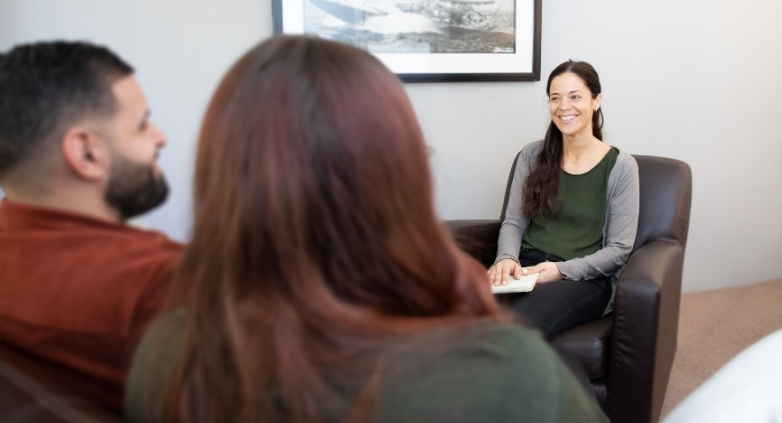 A woman sitting with a couple, focused on family counseling for alcoholics and the need for professional assistance.