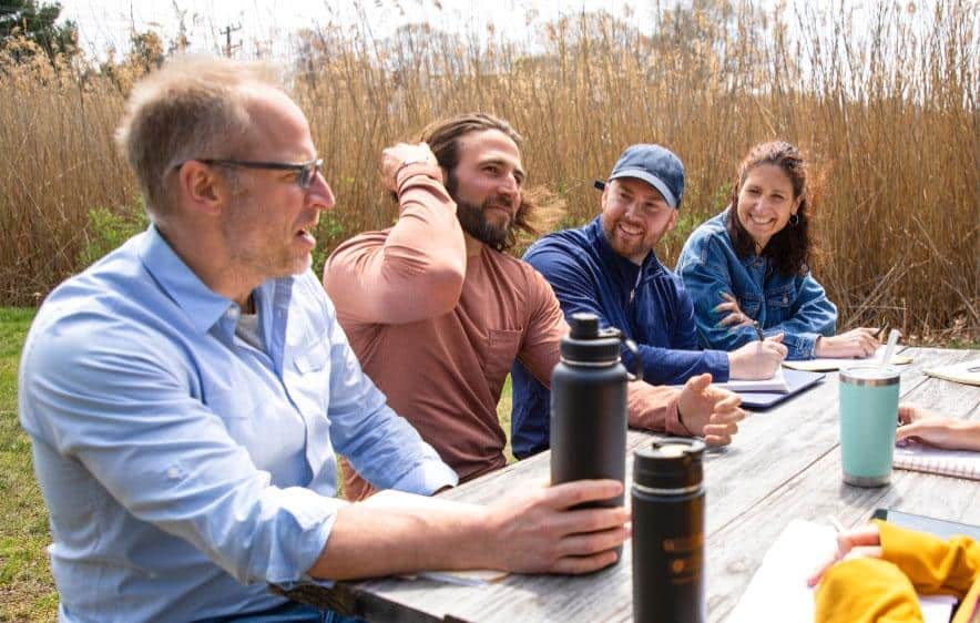 Group at picnic table, discussing family counseling for addiction in Connecticut.