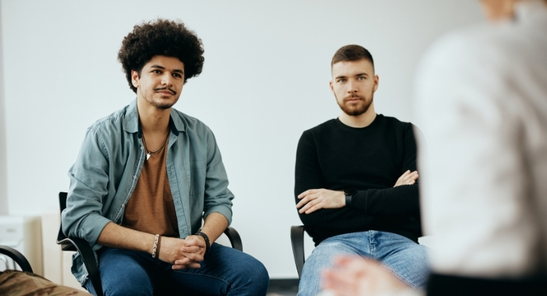 A group of people conversing in a room, focusing on forgiveness as a key element in addiction recovery discussions.