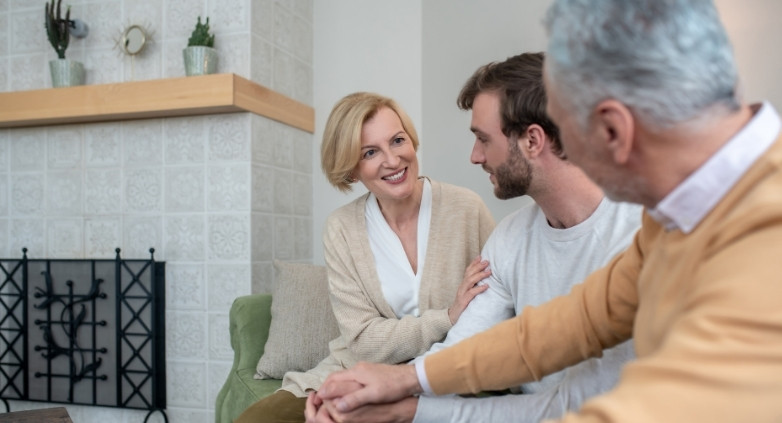 A Family sit together on a couch, engaging in a conversation about forgiveness and family healing in addiction recovery.