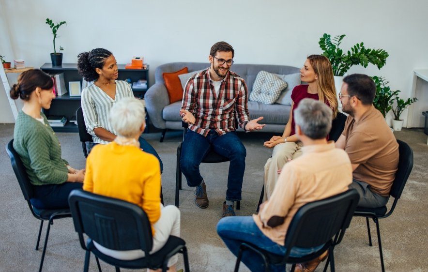Participants in a circle, actively conversing in a group therapy setting focused on alcohol abuse recovery.