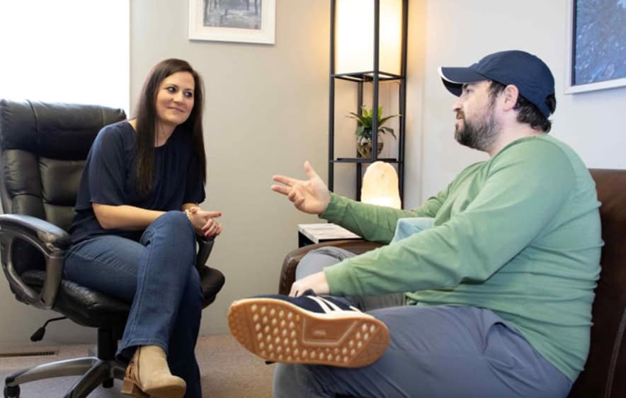 Office scene with man and woman discussing high-end drug rehab options.
