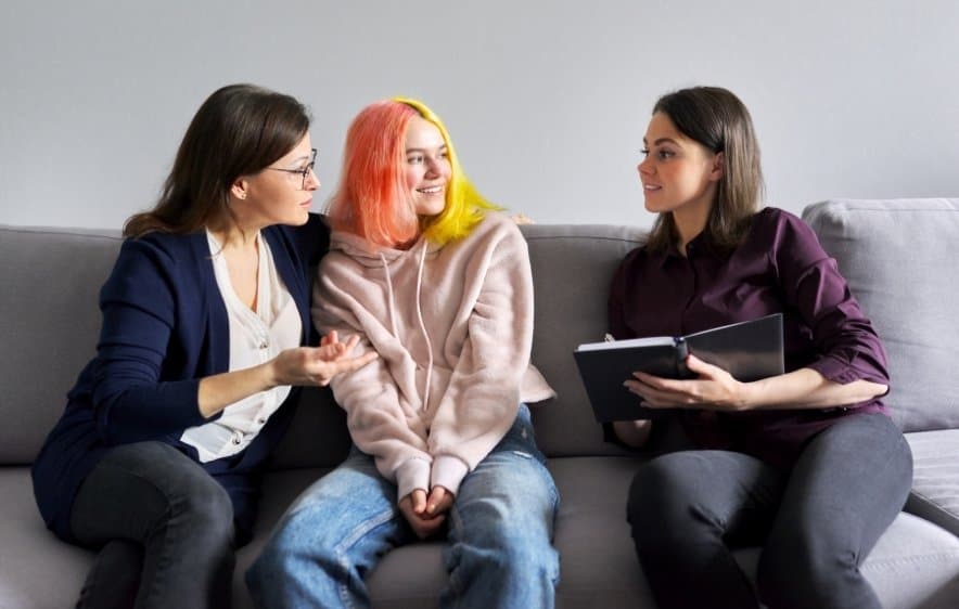 Parent and teen meeting with a counselor for family support during alcohol recovery
