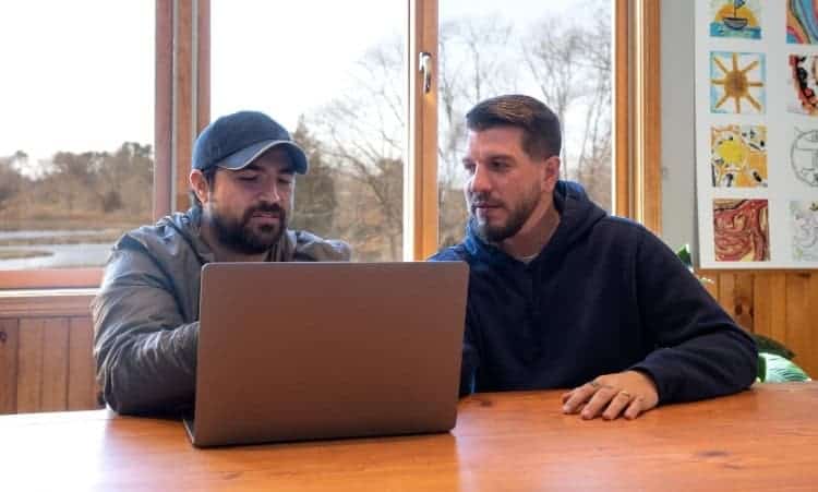 Two men reviewing recovery plans on a laptop during outpatient therapy in Chester, CT